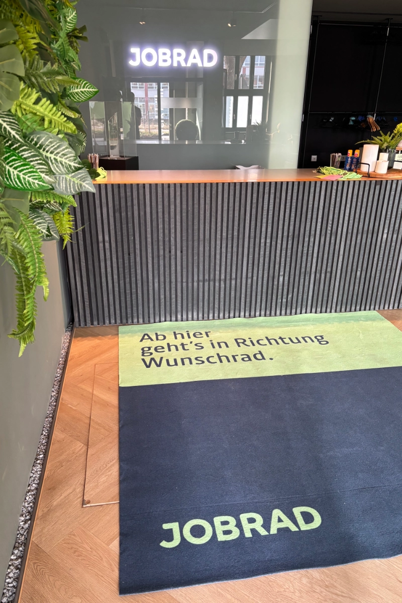 Blick auf Empfang, davor Teppich mit Schrift Ab hier geht's in Richtung Wunschrad.