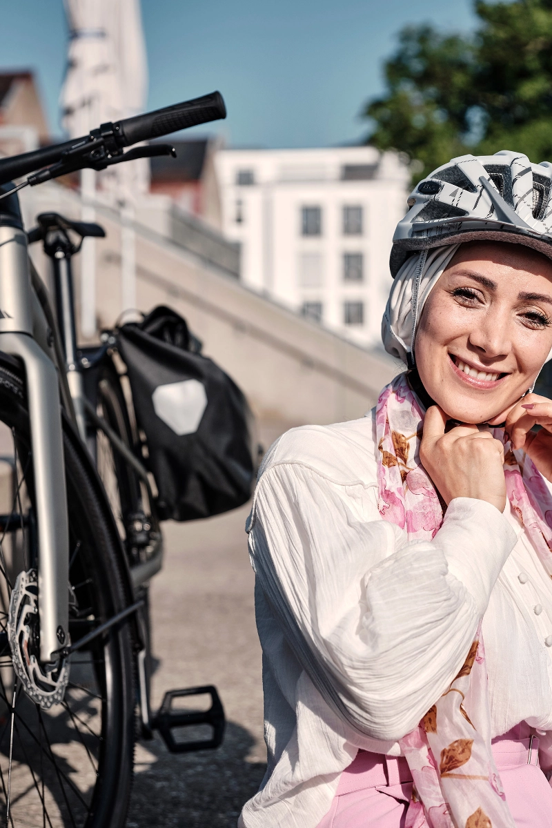 Frau sitzt mit Helm und Fahrrad in der Sonne