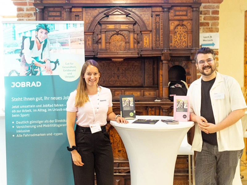 JobRad auf der Forum Kommunal 2024, links im Bild steht ein JobRad Plakat mit dem Schriftzug "Gut für Gesundheit, Geldbeutel und Umwelt! Steht ihnen gut ihr neues JobRad!"