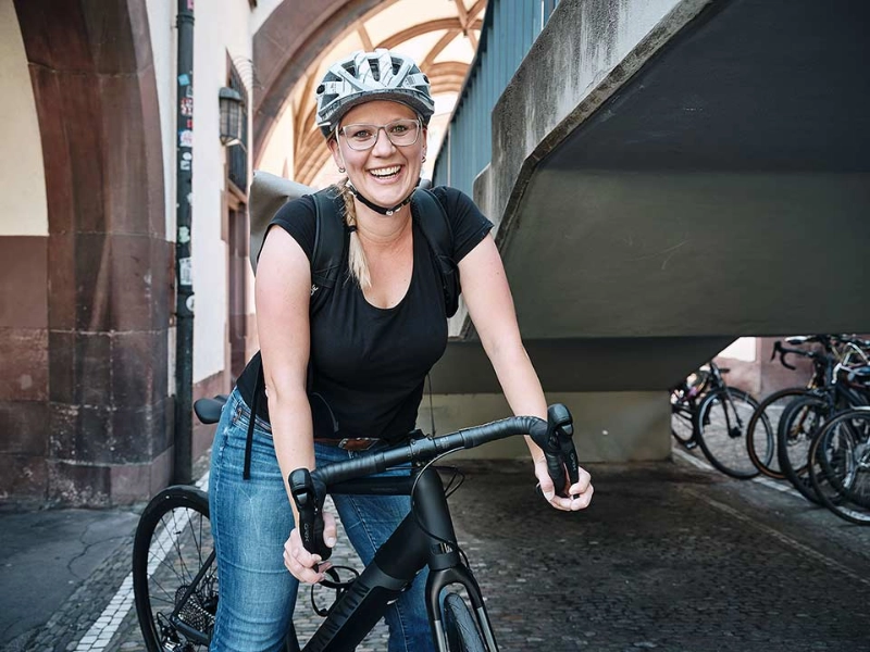 Eine lachende Frau auf ihrem schwarzen Fahrrad Eine lachende Frau auf ihrem schwarzen Fahrrad