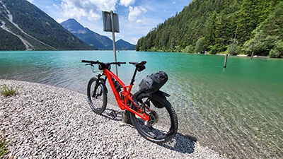 Rotes Mountainbike vor einem See, im Hintergrund die Österreicher Alpen.