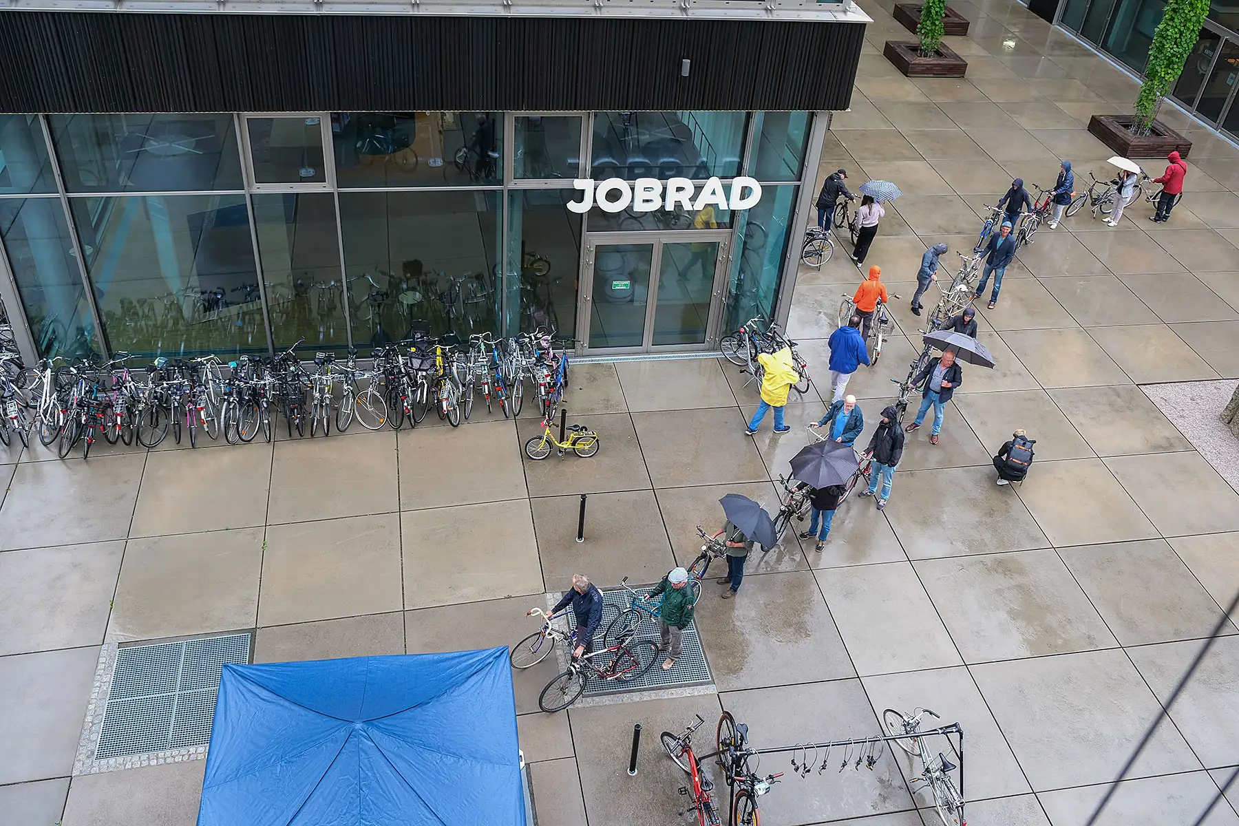 Eine lange Schlange von Menschen mit Fahrrädern und Regenschirmen auf dem JobRad Campus Eine lange Schlange von Menschen mit Fahrrädern und Regenschirmen auf dem JobRad Campus