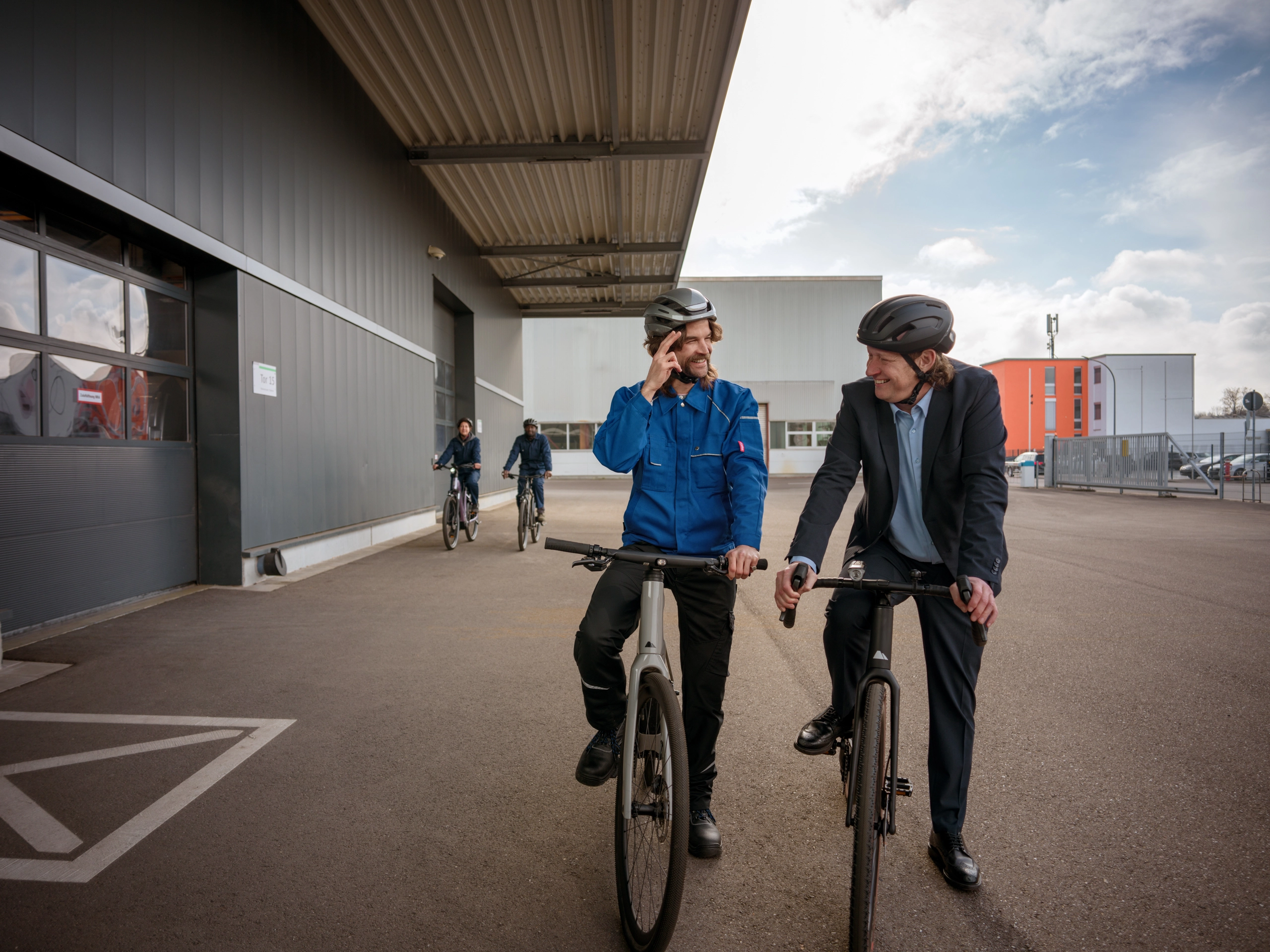 Mitarbeitende steigen zum Feierabend aufs Fahrrad auf einem Industriegelände