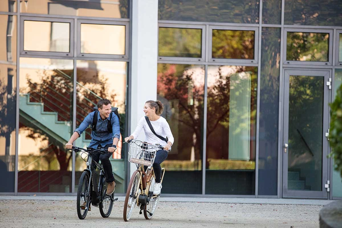Zwei Radfahrer:innen fahren zufrieden in den Feierabend Zwei Radfahrer:innen fahren zufrieden in den Feierabend